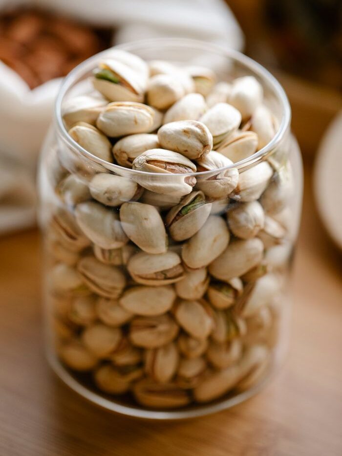 Close-up of pistachios in a glass jar, showcasing healthy snacking options.